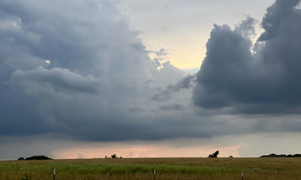Billowing clouds breaking over a prairie landscape at sunset